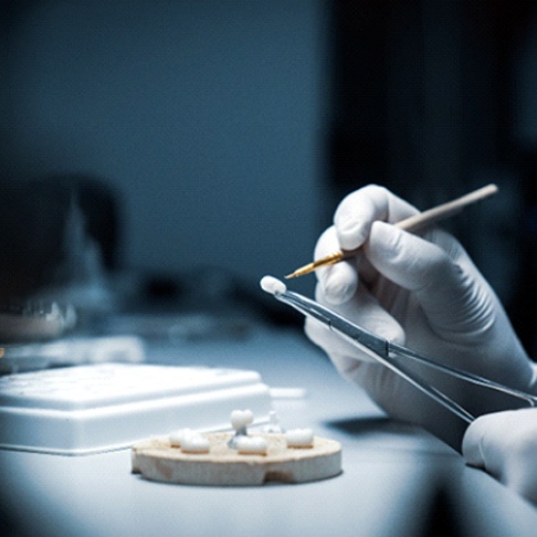 a laboratory technician hand-crafting a dental crown