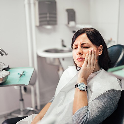 A woman with a toothache sitting in a dentist’s chair