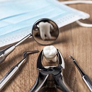 Dental forceps holding an extracted tooth next to other dental tools