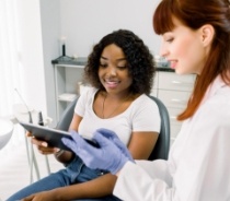 Dentist and dental patient looking at tablet computer together