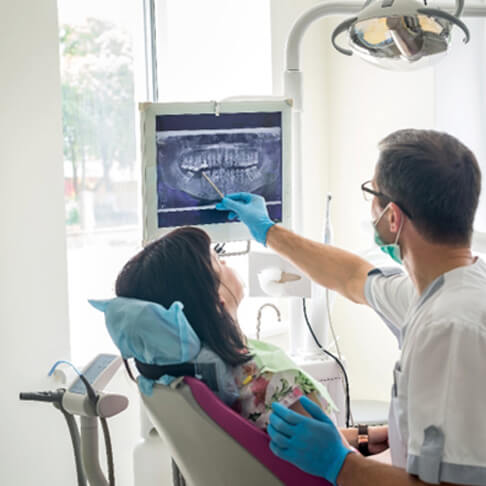 dentist in blue gloves showing xray results to patient with dark hair