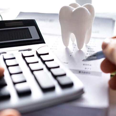 a person using a calculator next to a receipt and a large plastic tooth