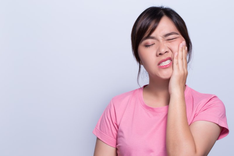 person with toothache holding cheek